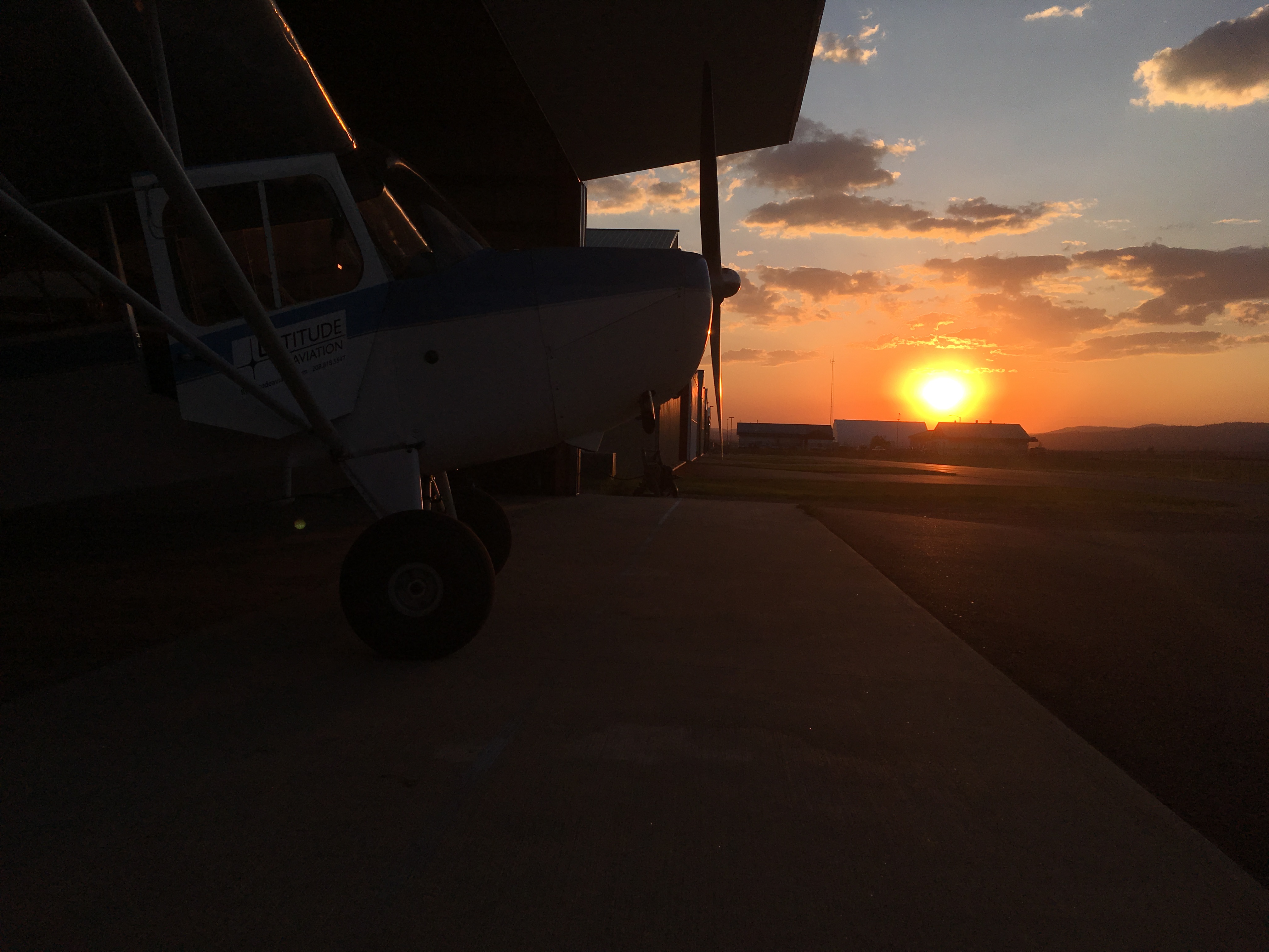  image of a small airplane during sunset just sticking out of a hangar